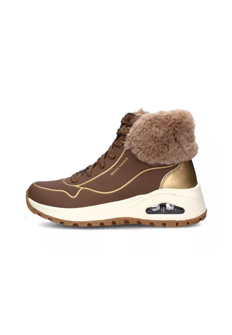 Bota deportiva marrón con cuello de pelo sintético, acentos dorados y entresuela blanca. Presenta un material texturizado y una burbuja de aire visible en el talón.