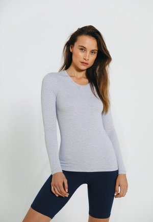 Lys grå langærmet skjorte i blødt stof, tætsiddende design. Sammen med navy blå cykelshorts, der viser en glat tekstur og afslappet stil.