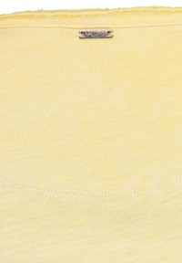 Top de tejido amarillo con acabado texturizado, con escote redondo y una pequeña etiqueta plateada "Key Largo". Sin patrones visibles.