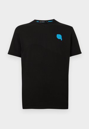 T-shirt noir à manches courtes et col ras du cou, avec un petit logo brodé bleu en forme de visage sur le côté gauche de la poitrine.