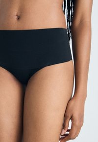 Culotte da bikini nera a vita alta con texture liscia, design minimalista e fascia elastica; si concentra su comfort e vestibilità.
