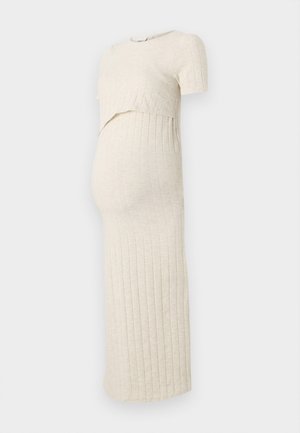 Vestido de maternidade em bege claro com textura canelada. Apresenta um top curto e uma saia justa, desenhado para acomodar uma barriga em crescimento.