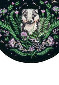 Embroidered patch featuring a badger surrounded by green ferns and purple flowers on a black background, highlighting detailed stitching and textures.
