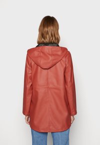 Rode jas van imitatieleer met capuchon, voorzien van een zwarte kraag, lange mouwen en een losse pasvorm. Gladde textuur en eenvoudig ontwerp.