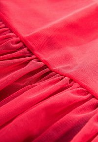Tessuto rosa che presenta uno strato superiore liscio e una texture di rete arricciata sottostante, con sottili variazioni di tonalità e morbidezza in tutto il materiale.
