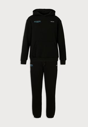 Crna trenirka s kapuljačom, kangur džepom i pripadajućim trenirka hlačama, obje sa sitnim bijelo-plavim tiskanim logotipovima.