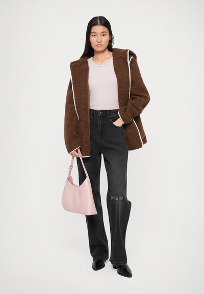 Chaqueta marrón de felpa con ribetes blancos, top rosa ajustado, jeans de pierna ancha negros y bolsa de hombro rosa. Tacones negros completan el look.