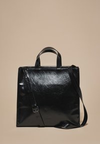 Zwarte leren totebag met een glanzende afwerking, voorzien van korte handvatten en een verstelbare schouderriem. Vierkante vorm, minimalistisch ontwerp.