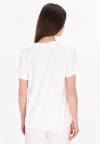 Hvid kortærmet t-shirt med rund hals, der har rullede ærmer og en glat tekstur, vist fra bagsiden med en lige skæring.