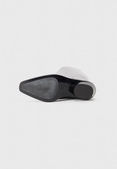 Musthave mustad mustakega, millel on sujuv valge ülemine osa, ümmargune varvas ja sleek-kumer siluett. Tallad on mattmustad ja tekstuuriga viimistlusega.