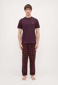 Burgundi puuvillane T-särk musta kaelusega, kombineeritud laia lõikega ruuduliste öösärkide pükstega tumepunases ja valges, millel on elastne vöökoht.