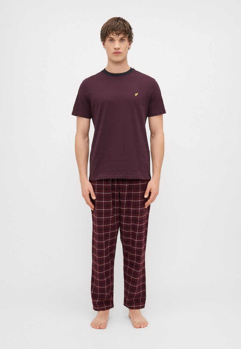 Burgundi puuvillane T-särk musta kaelusega, kombineeritud laia lõikega ruuduliste öösärkide pükstega tumepunases ja valges, millel on elastne vöökoht.