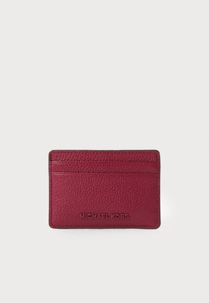 Burgundy cardholder with textured leather, featuring multiple slots and embossed "MICHAEL KORS" logo at the front.