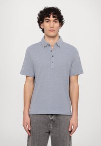 Short-sleeve polo shirt in light blue, made of a soft fabric. Features a collar, button placket, and a relaxed fit. Textured surface.