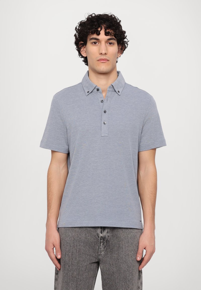 Short-sleeve polo shirt in light blue, made of a soft fabric. Features a collar, button placket, and a relaxed fit. Textured surface.
