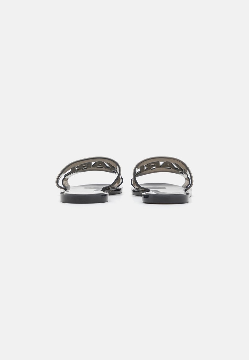 Schwarze Rutschsandalen mit glatter, matter Oberfläche und abgerundeten Riemen mit ausgeschnittenem Branding. Die flachen Sohlen sorgen für eine minimale Erhöhung.