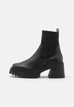 Botines negros hasta el tobillo con exterior de cuero liso, paneles laterales elásticos, tacón grueso de bloque y suela de goma texturizada.