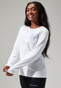Langärmliges weißes T-Shirt mit einem runden blauen Grafikmotiv, das Berge und Sonne zeigt. Hat einen lässigen Schnitt und eine weiche Baumwolltextur.