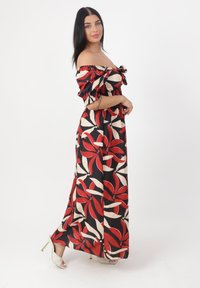 Maxikjole med blomstermønster i rød, creme og sort. Off-the-shoulder design med pufærmer og smocket talje.