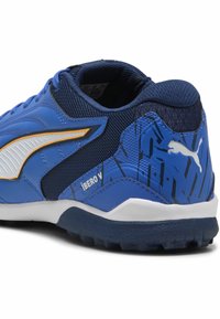 Zilas sporta apavu modelis ar strukturētu, sieta augšdaļu un sintētiskām akcentiem. Iezīmē balta svītra, oranžas detaļas un rakstainu papēdi.