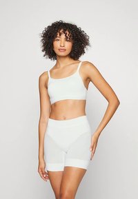 Biały biustonosz i dopasowane szorty z wysokim stanem, wykonane z gładkiego, elastycznego materiału. Prosty design z cienkimi ramiączkami, bez wzorów i ozdób.