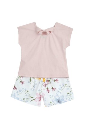 Różowa bawełniana bluzka z krótkimi rękawami i kokardą z tyłu, w połączeniu z białymi szortami z kolorowym wzorem w kwiaty i zielonymi akcentami.