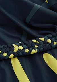 Námorná látka so žltými akcentmi obsahuje splietaný pás v zelených, žltých a námorných farbách. Hladká textúra, prítomné geometrické vzory.