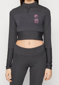 Grå, långärmad cropped tröja med halvdragkedja och ribbad textur. Har en rosa logotyp och textdetalj på bröstområdet.