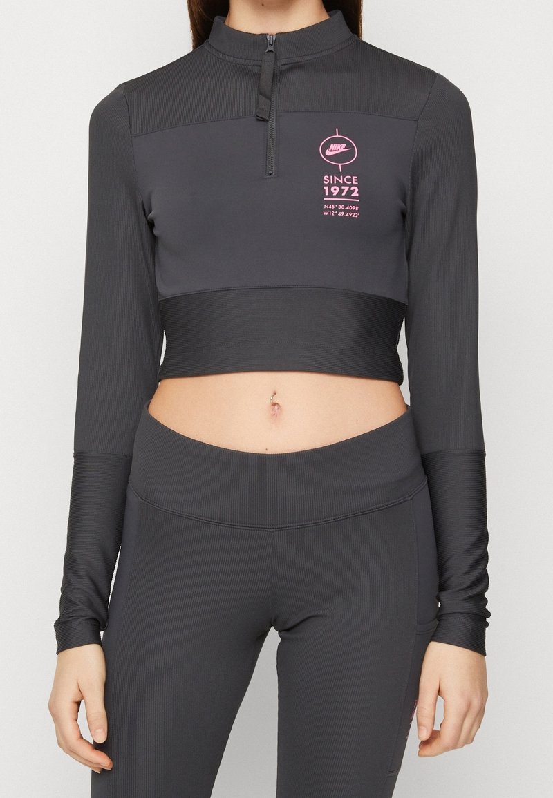 Grå, långärmad cropped tröja med halvdragkedja och ribbad textur. Har en rosa logotyp och textdetalj på bröstområdet.