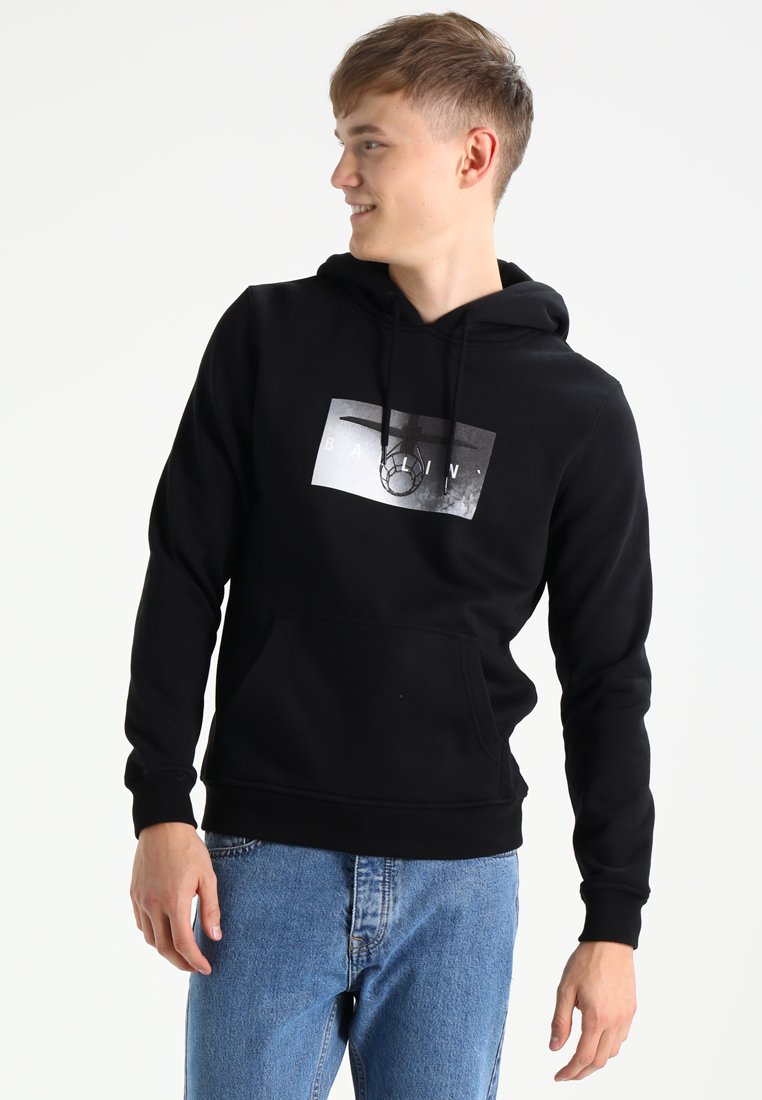 Zwarte hoodie van katoenmix met een voorkant kangaroo pocket, voorzien van een monochroom grafisch ontwerp op de borst. Blauwe spijkerbroek completeert de outfit.