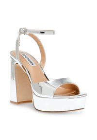 Metallic sølv platform hælsandaler med åben tå, ankelrem og kraftig hæl. Glat tekstur og blank finish. Brandlogo synligt.