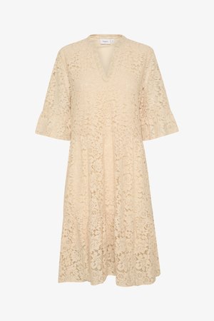 Kremkrāsas mežģīņu kleita ar V veida kaklu, platām piedurknēm un pakāpenisku svārku. Ziedu raksts visā kleitā, izceļot sarežģītas mežģīņu detaļas.