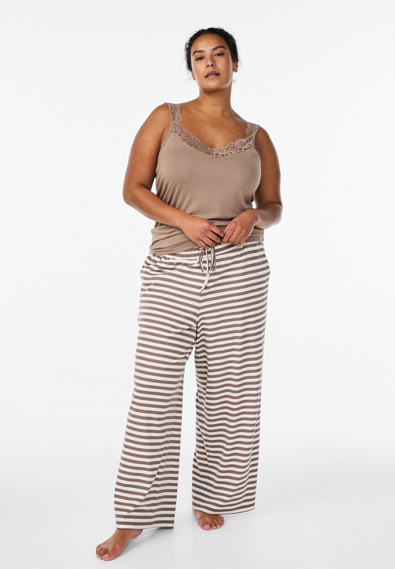 Jasnobrązowy top na ramiączkach z koronkową lamówką, połączony z beżowo-białymi pasiastymi spodniami do piżamy. Oba wykonane z miękkiego, lekkiego materiału.