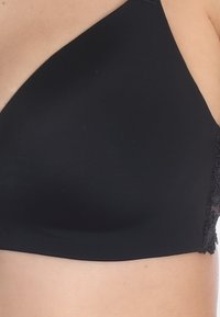 Zwarte bralette van gladde stof met een kanten detail aan de zijkant en een asymmetrisch bandontwerp.
