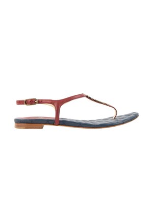 Sandale plate avec des lanières en cuir rouge, une semelle intérieure matelassée bleu marine, une boucle dorée et une fine semelle marron, vue de côté.