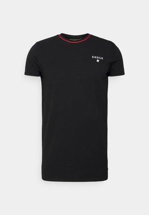 T-shirt noir à manches courtes et col rond avec petit logo blanc "SIKSILK" et emblème sur la poitrine, bordure rouge autour du col.
