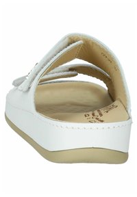 Sandalia blanca con parte trasera abierta, cinta acolchada y suela beige. Presenta un acabado liso y un sutil detalle de costura.