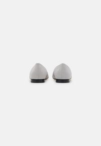 Ballerine in suede grigio con punta arrotondata, design minimalista, tacco nero basso e dettagli cuciti sulla cucitura posteriore.