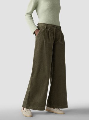 Person wearing high-waist wide-leg olive corduroy pants, light green textured long-sleeve top, and beige loafers. Hands in pockets.