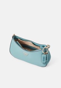 Světle modrá kabelka z texturovaného materiálu, se zipovým uzávěrem, vnitřními přihrádkami a kovovým logem na přední straně.