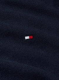 Tissu en maille bleu marine présentant un petit logo brodé avec des accents rouges et blancs, mettant en valeur une surface texturée et un tissage serré.