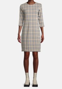 Rutig klänning i beige, svart och gult med rund halsringning och trekvartslånga ärmar. Matchad med beige ankelstövlar.