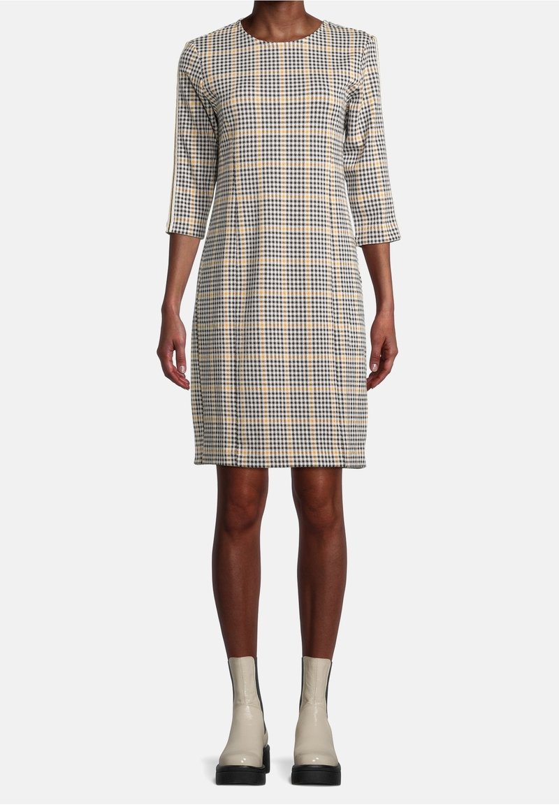 Rutig klänning i beige, svart och gult med rund halsringning och trekvartslånga ärmar. Matchad med beige ankelstövlar.