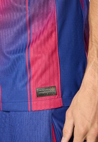 Kortärmad atletisk tröja med ett gradientdesign i lila och rosa färger, texturerat material och en guldfolierad varumärkesetikett.