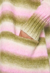 Pull en tricot avec des rayures horizontales vertes, roses et blanches. Comprend des poignets côtelés et une poche à l'avant. Texture douce.