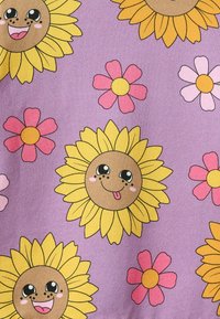 Tessuto a motivi con grandi girasoli sorridenti con facce da cartone animato in giallo e marrone su uno sfondo lavanda, intervallato da fiori rosa.