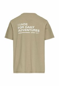 Beige kortærmet t-shirt med rund hals, med hvid tekst på ryggen: "LAVET TIL DAGLIGE EVENTYR Siden 1977." Blød bomuldsstruktur.
