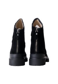 Stivaletti in camoscio nero con zip laterale, punta rotonda e suola in gomma testurizzata. Fodera interna liscia, design minimale senza dettagli.