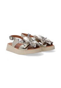 Metalen gouden sandalen met grote strikken, open teen ontwerp, verstelbare enkelband, rubberen zool en een gepolsterde voetbed voor comfort.