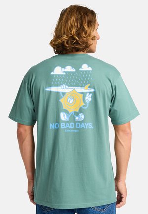 Grøn bomuld t-shirt med et grafik af en smilende sol med et surfbræt, skyer, regn og teksten "NO BAD DAYS" i blå. Afslappet pasform.